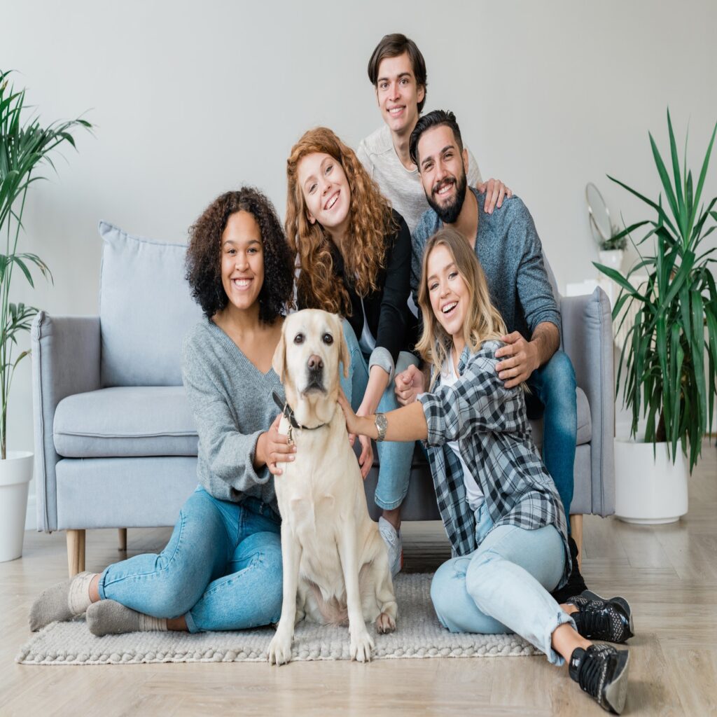 Cheerful young friendly companions and their cute pet relaxing at home